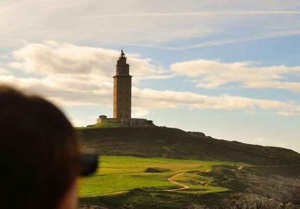 Mujer observando la Torre de Hércules en A Coruña durante su escapada romántica